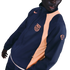 A person wearing a navy blue Nike FC Barcelona windbreaker with peach accents and the team's crest on the chest.