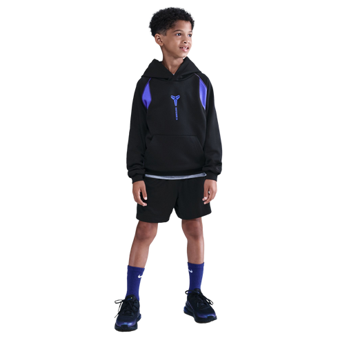 A young boy wearing a black and purple hoodie, black shorts, and purple socks stands against a solid black background.
