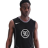 A young Black man wearing a black Nike sleeveless jersey with the number 90 in a white circle, against a solid black background.