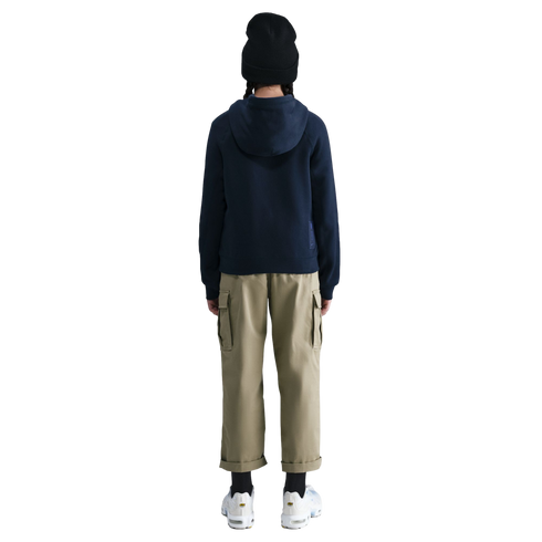 Rear view of a person wearing a black beanie, navy hoodie, tan cargo pants, and white sneakers against a black background.