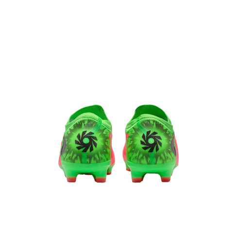 Rear view of a pair of neon green and orange soccer cleats, featuring a black circular graphic on the heels against a black background.