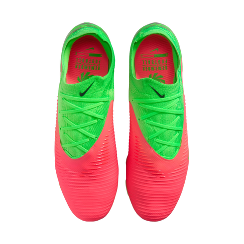 A top-down view of a pair of neon green and bright pink Nike soccer cleats against a solid black background. The front of the boots is pink with horizontal ridges, transitioning to a neon green upper with matching green laces and a small black Nike swoosh