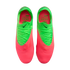 A top-down view of a pair of neon green and bright pink Nike soccer cleats against a solid black background. The front of the boots is pink with horizontal ridges, transitioning to a neon green upper with matching green laces and a small black Nike swoosh