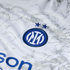 Close-up of a white Inter Milan jersey featuring the blue and white club crest with two stars above it on a subtle grey-patterned fabric.