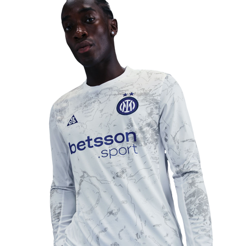 A man wears a long-sleeved white Inter Milan jersey with a gray marbled design and "betsson.sport" logo, set against a black background.