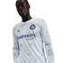 A man wears a long-sleeved white Inter Milan jersey with a gray marbled design and "betsson.sport" logo, set against a black background.