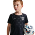 A young boy with red hair wearing a navy blue USA national team soccer jersey with a star pattern, holding a soccer ball.
