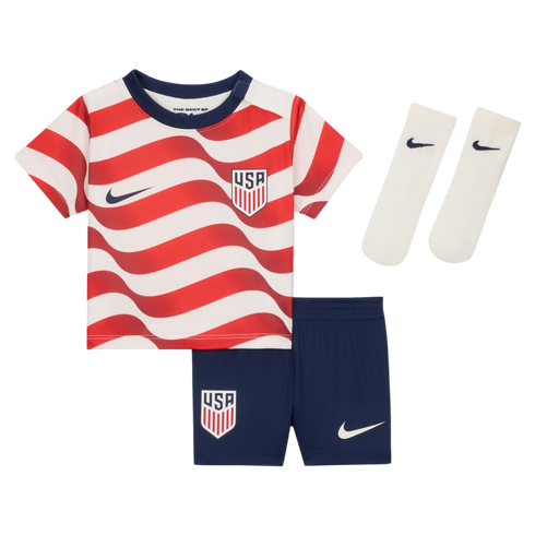 A kids' USA soccer kit featuring a red and white wavy-striped jersey, navy shorts, and white socks, all with Nike swooshes and USA crests.