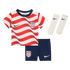 A kids' USA soccer kit featuring a red and white wavy-striped jersey, navy shorts, and white socks, all with Nike swooshes and USA crests.