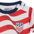 Close-up of a baby shirt with red and white wavy stripes, a navy blue collar, shoulder snaps, and the USA soccer team crest on the chest.