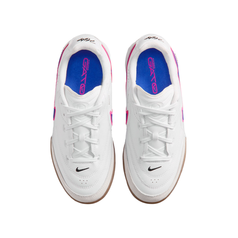 Top-down view of white Nike Gato indoor soccer shoes with blue insoles and pink accents, set against a black background.