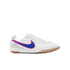 White Nike Tiempo indoor soccer shoe with a blue and pink swoosh and gum rubber sole, shown from the side against a black background.
