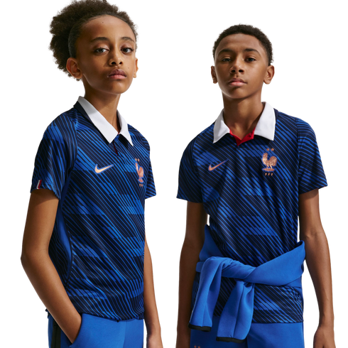 Two youths wear blue France national team jerseys with white collars and diagonal stripes. The shirts feature the FFF rooster crest. Solid black background.