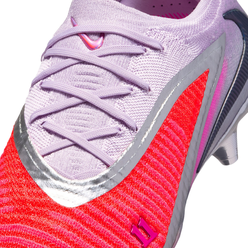 Close-up of a Nike soccer cleat with a light purple knit upper, matching laces, and a vibrant red-orange textured section outlined in silver.