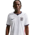 A waist-up portrait of a young man with braided hair wearing a white Nike England national football team home jersey against a solid black background.