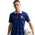 A man wearing a blue Nike France national team soccer jersey with a white collar, holding a white soccer ball against a black background.
