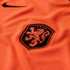 A close-up of an orange ribbed sports jersey featuring a black Nike swoosh in the upper left corner and the Netherlands national football team crest, a shield with an orange lion on a black background and the letters "KNVB."