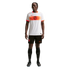 A full-length portrait of a male athlete wearing a Netherlands national soccer team away kit, standing against a solid black background. He is wearing a white jersey with an orange horizontal stripe across the chest, black shorts, and black knee-high sock