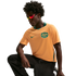 A man wearing an orange and green Australia national soccer jersey and red-tinted sunglasses crouches against a black background.