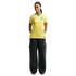 A woman with braided hair wearing a yellow Brazil national soccer team jersey and dark cargo pants, standing against a black background.