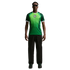A man wearing a green and white Nigeria football jersey, black pants, and sunglasses, standing against a black background.