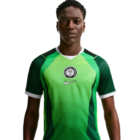 Man wearing a green Nigeria national football team home jersey with a circular federation crest and white Nike swoosh, set against a black background.