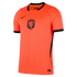 A front-facing studio shot of a bright orange Nike football jersey for the Netherlands national team. The jersey features a black V-neck collar, black sleeve cuffs, a black Nike swoosh on the chest, and the KNVB crest with a red lion in the center.