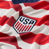 Close-up of a red and white striped soccer jersey with an embroidered shield crest featuring blue "USA" lettering and red vertical stripes.