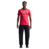A man stands in a red England national football team jersey and black trousers against a plain black background.