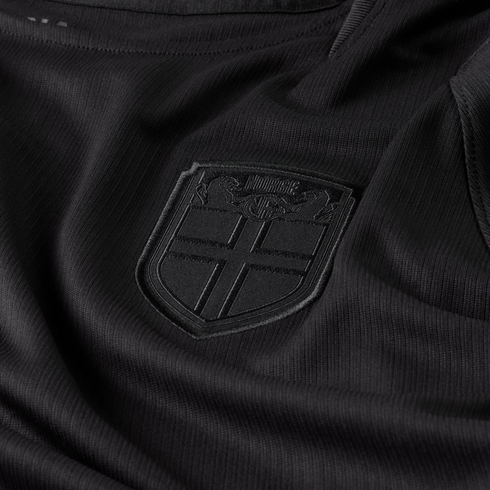 Close-up of a black textured jersey featuring an all-black embossed crest with a cross and the word "NORGE."