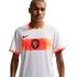 A waist-up portrait of a man wearing a white Netherlands national football team away jersey. The jersey features a wide orange band across the chest with a central lion crest and a black Nike logo on the right. The man has short-cropped hair, a mustache,