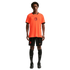 A male model stands against a black background wearing a bright orange Netherlands national team soccer jersey with black trim, matching black shorts, high black socks, and black cleats.