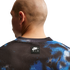 Close-up of the back of a bald man in a black and blue mesh Nike Air jersey with a small logo on the center back.