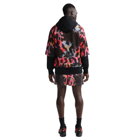 Rear view of a man wearing a black hoodie under a colorful abstract-print mesh jersey with matching shorts, black socks, and sneakers on a white background.