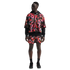 A man wears a multicolored Nike Air mesh jersey and matching shorts layered over a black hoodie and black sneakers against a white background.