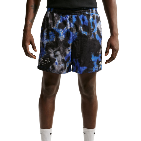 A person wearing Nike athletic shorts with a blue, black, and grey pixelated abstract pattern and white Nike socks, shown from the waist down against a plain white background.