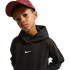 A boy wearing a black Nike hoodie and a maroon Nike baseball cap looks at the camera against a black background.