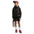 A young boy in a black Nike hoodie, black shorts, maroon cap, and maroon sneakers stands against a black background, holding a silver water bottle and wearing wired earphones.