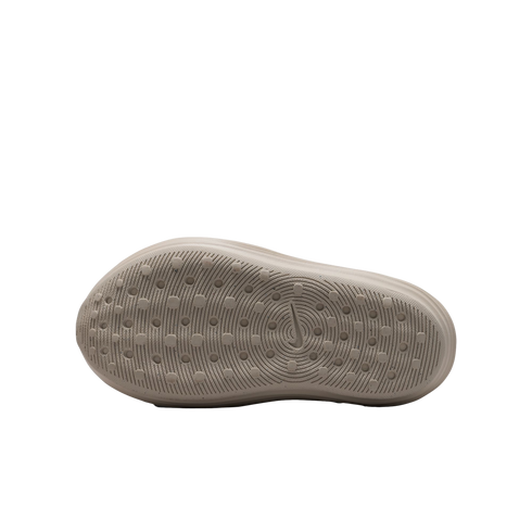 The light beige underside of a Nike shoe featuring a textured traction pattern of concentric circles and small lugs on a solid black background.