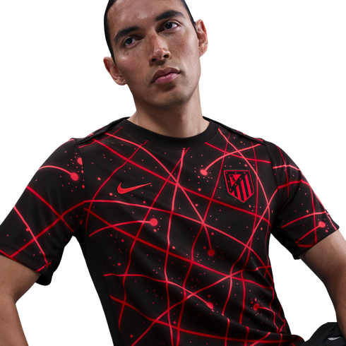 A man wearing a black Nike Atlético Madrid jersey featuring an abstract red geometric line pattern.
