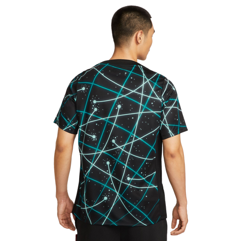 Back view of a man wearing a black short-sleeve shirt with a teal geometric line and dot pattern, standing against a white background.