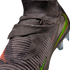 A close-up shot of a dark grey Nike soccer cleat featuring a textured, knitted upper and iridescent green and orange Nike swooshes against a solid black background.