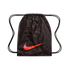 A dark brown Nike drawstring bag featuring a large, bright red swoosh across the center. The bag is covered in a repeating black text pattern of "NIKE" followed by translations for the word "football" in various languages and scripts. Black cord drawstrin