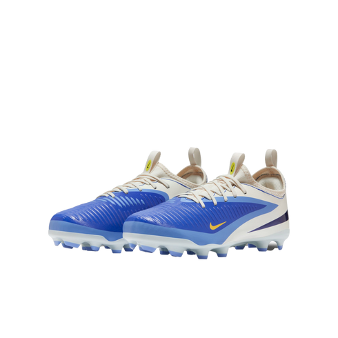 A pair of blue and cream Nike soccer cleats with yellow accents and a textured upper, shown against a solid black background.