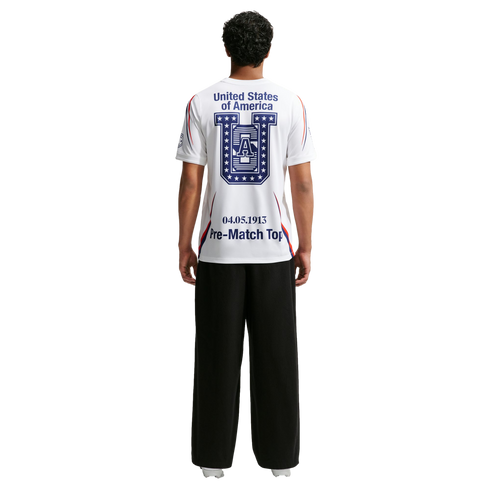Rear view of a person wearing a white t-shirt with "United States of America" and a large blue logo on the back, paired with black wide-leg trousers.
