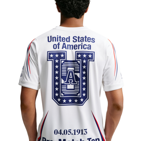 Rear view of a person wearing a white athletic shirt with "United States of America," a large blue star-patterned "U" graphic, and the date "04.05.1913" printed on the back.