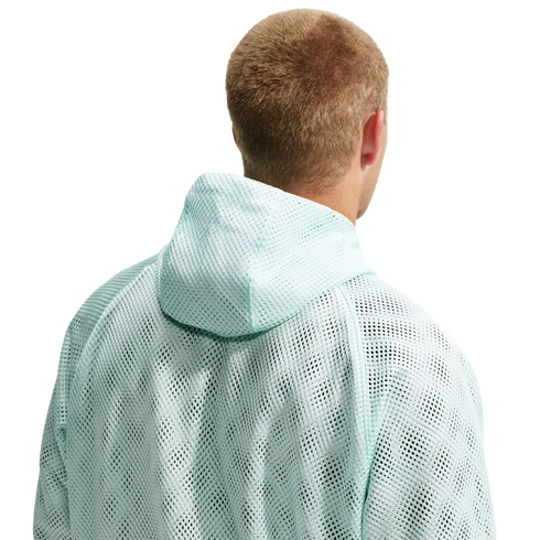 Rear view of a person with short blonde hair wearing a mint green mesh hooded sweatshirt against a black background.