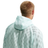 Rear view of a person with short blonde hair wearing a mint green mesh hooded sweatshirt against a black background.