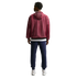 Full-body back view of a man wearing a maroon mesh hooded jacket, navy blue sweatpants, and white sneakers against a black background.