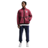 A full-length photo of a man modeling Nike USA soccer apparel against a black background. He wears a maroon hooded jacket with a white swoosh and USA crest, navy joggers with matching logos, and white sneakers.